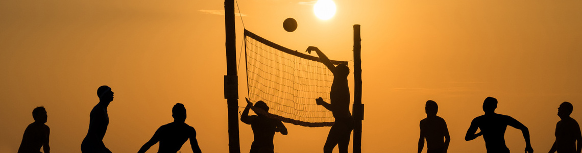 Silhouette Beachvolleyball spielender Menschen beim Sonnenuntergang.